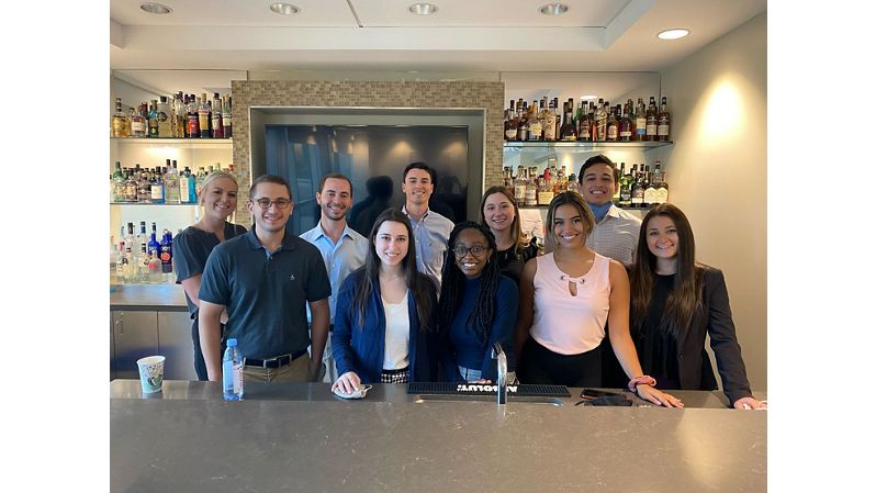Group of diverse interns standing behind bar