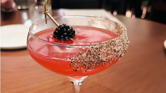 A close up of a creative cocktail, topped with edible garnish