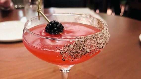 A close up of a creative cocktail, topped with edible garnish