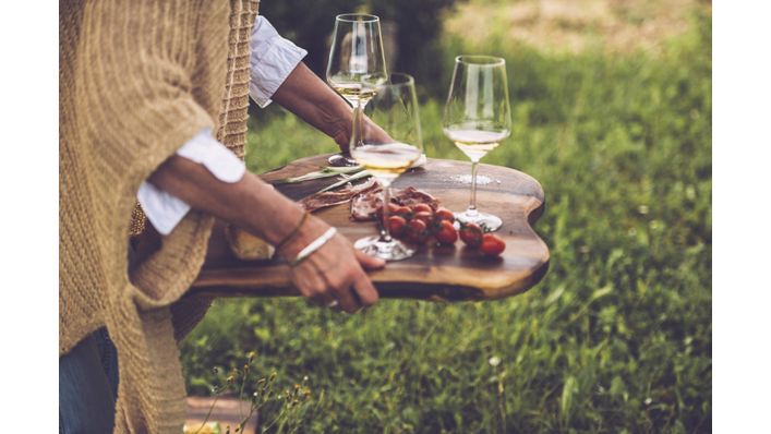 Glasses of wine and cherry tomatoes on a wooden serving tray
