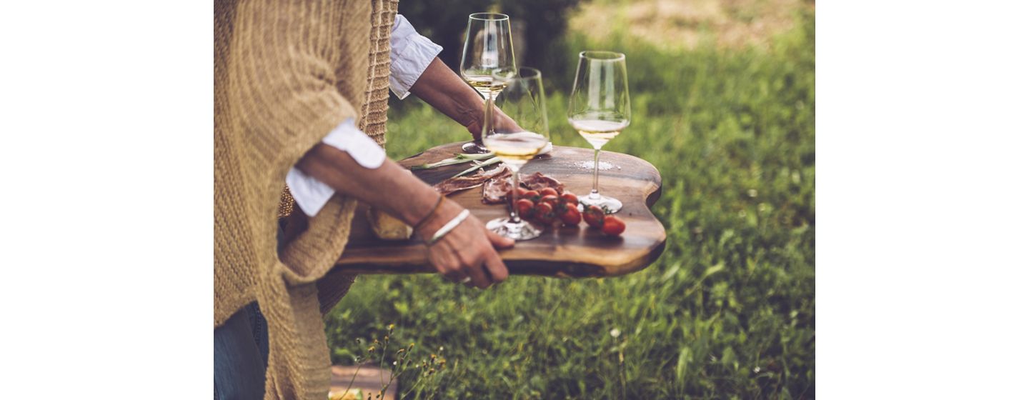 Glasses of wine and cherry tomatoes on a wooden serving tray