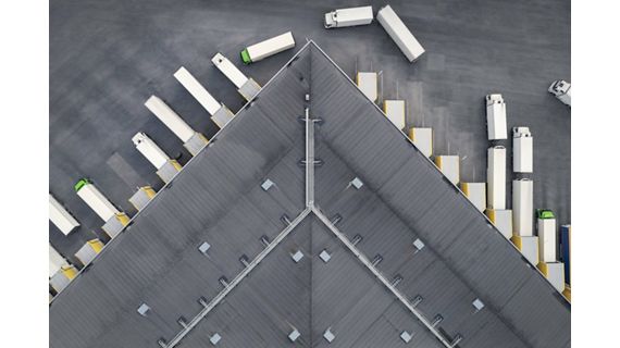 Aerial view of a large distribution warehouse with loading docks and many trucks.