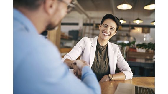 Shot of a man and woman shaking hands during a meeting in a coffee shop