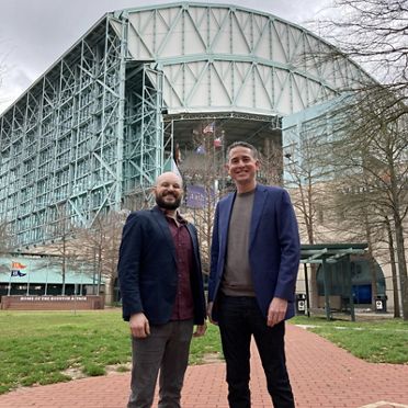 two men in front of large building