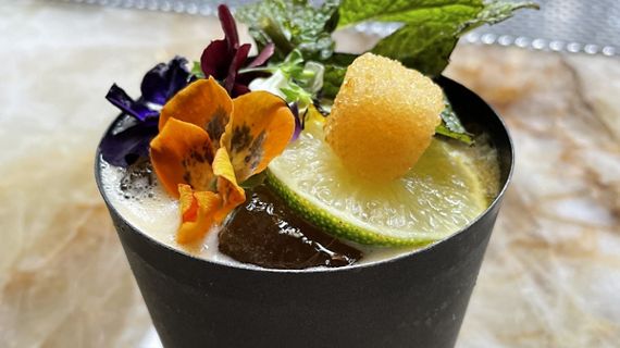 A close up of a creative Toca Madra cocktail, topped with vibrant and edible garnishes.