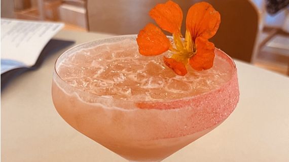 A close up of a creative cocktail, topped with flower garnish