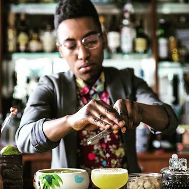 A focused bartender meticulously crafts cocktails in classic bar setting.