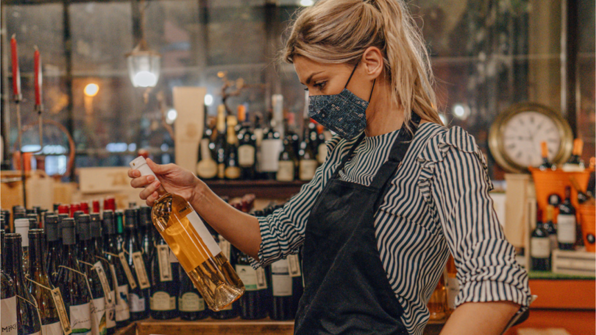 Female retail worker inspecting wine bottle