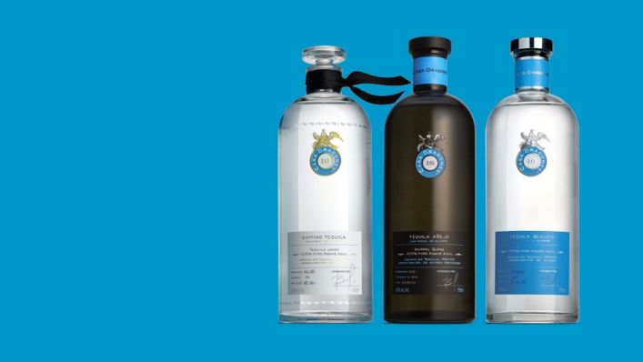 Three elegant bottles of Casa Dragones tequila on a simple background, with clear, blue, and dark glass.