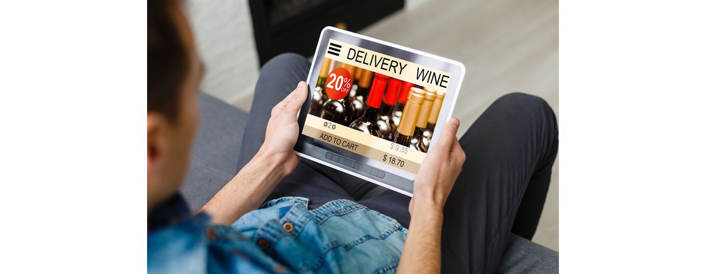 Close up of man holding an iPad looking at a delivery wine site