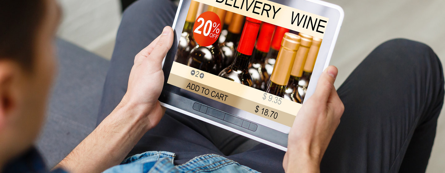 Close up of man holding an iPad looking at a delivery wine site
