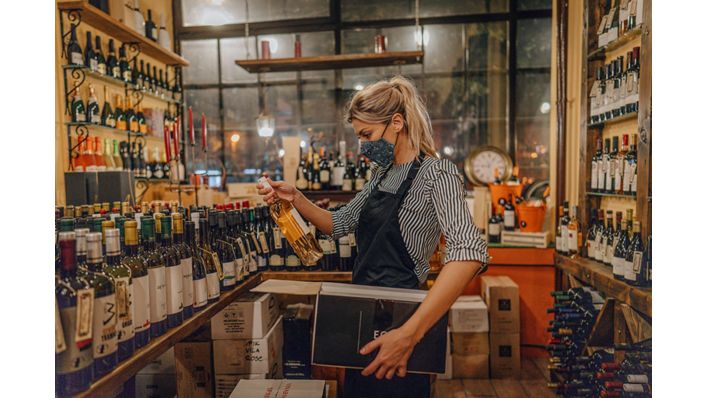 Female retail worker inspecting wine bottle