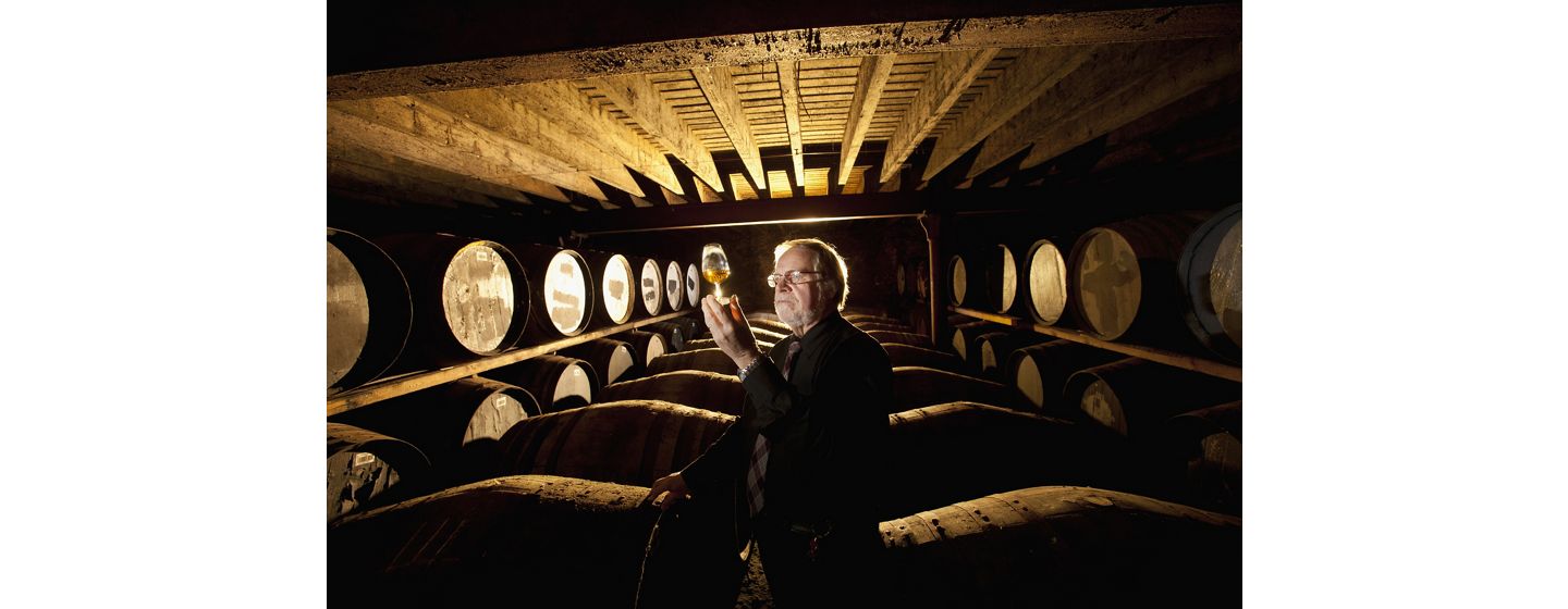 Man in cellar inspecting alcoholic beverage