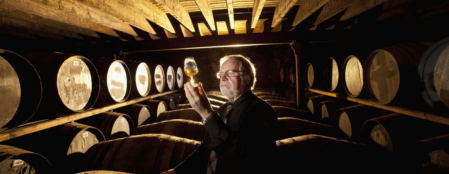 Man in cellar inspecting alcoholic beverage