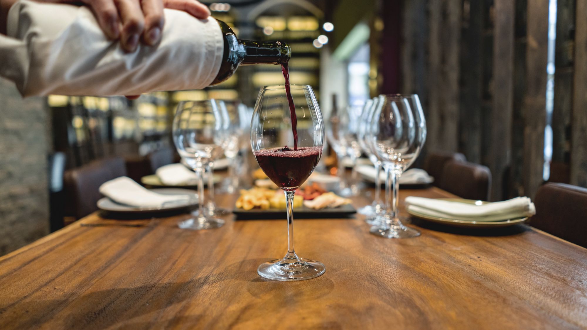 Close-up on a sommelier serving red wine at a winetasting â food and drinks concepts