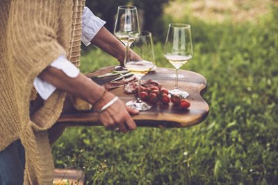 Glasses of wine and cherry tomatoes on a wooden serving tray