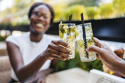 Beautiful young black couple drinking mojito cocktails in a bar outdoors. Having a celebratory toast.