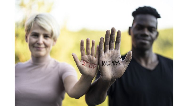 White woman and Black man with "Stop Racism" written on their hands.