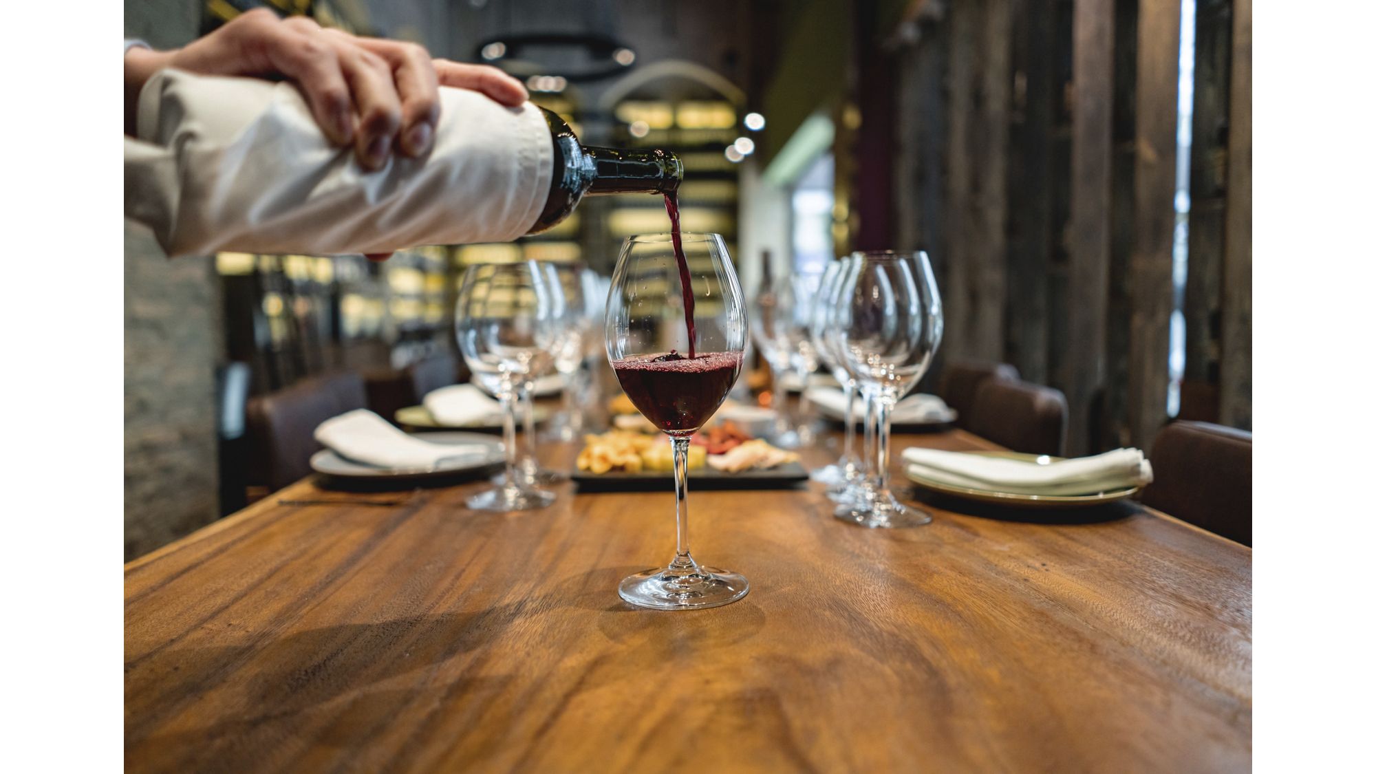 Close-up on a sommelier serving red wine at a winetasting â   food and drinks concepts